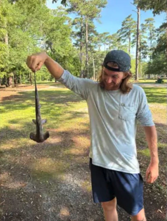 A disc golfer holds up a baby hammerhead shark dropped from the sky onto the course in South Carolina.
