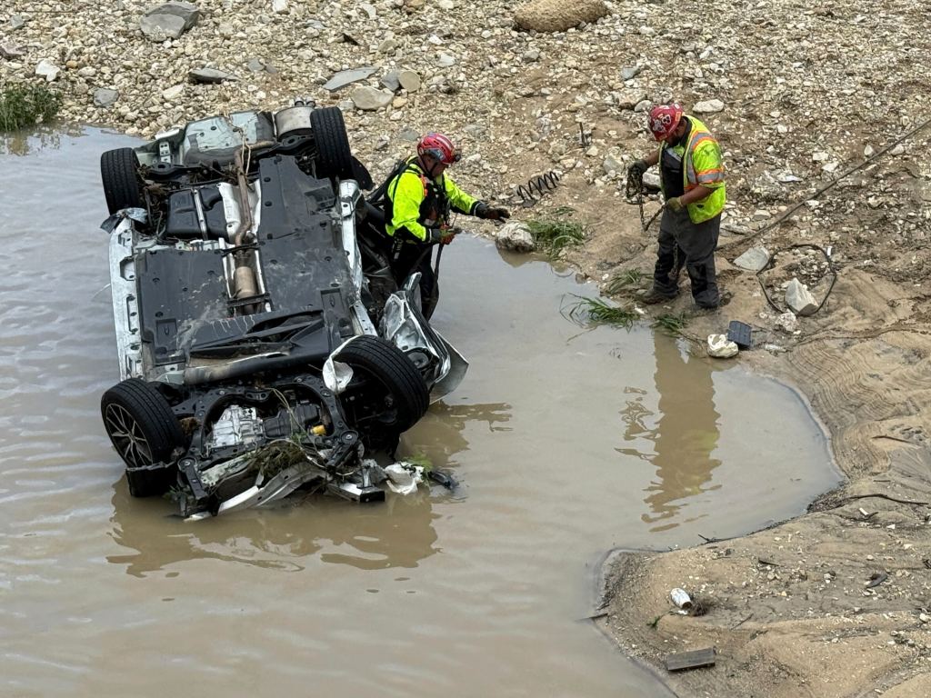 Rescue workers recovering an overturned car from floodwaters.