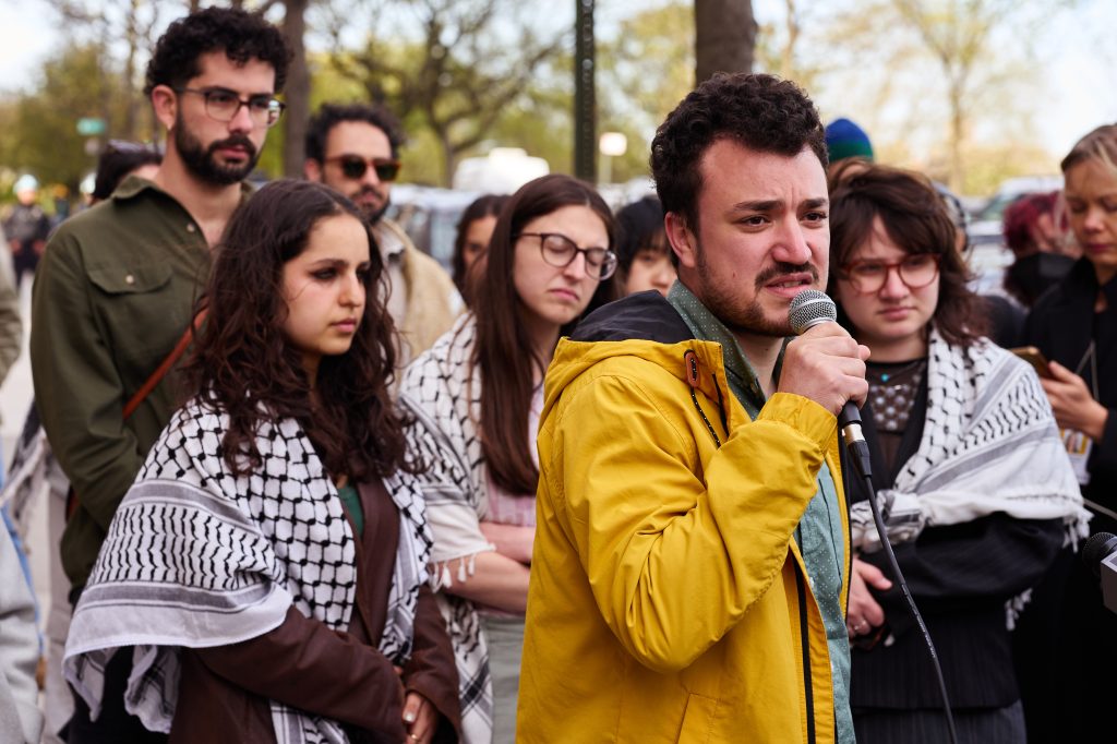 A man speaking into a microphone at a protest.