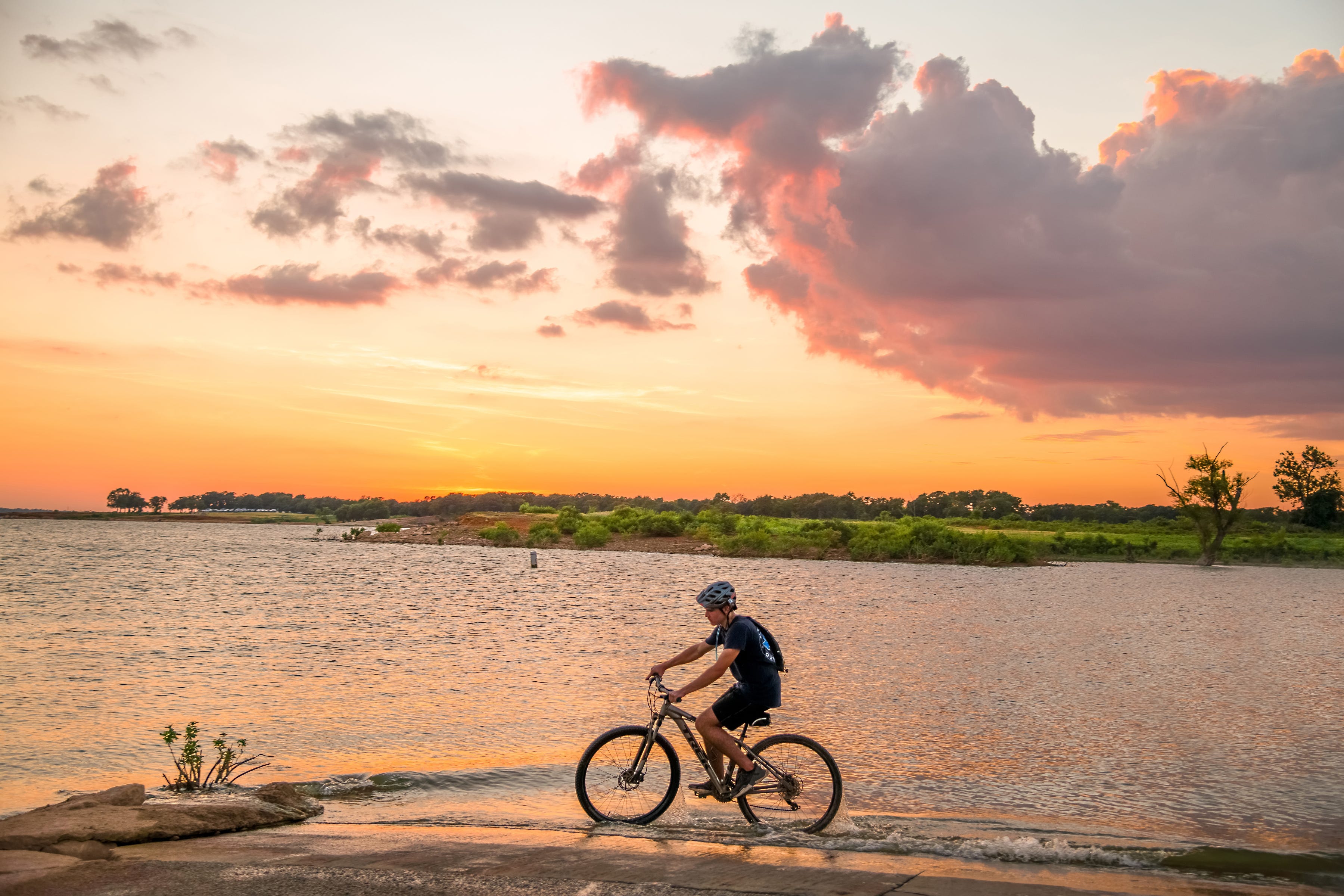 A person riding a bike along a lake.