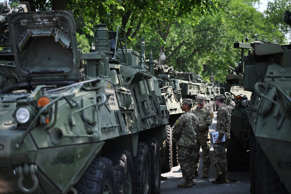 Soldiers standing near Stryker armored vehicles.