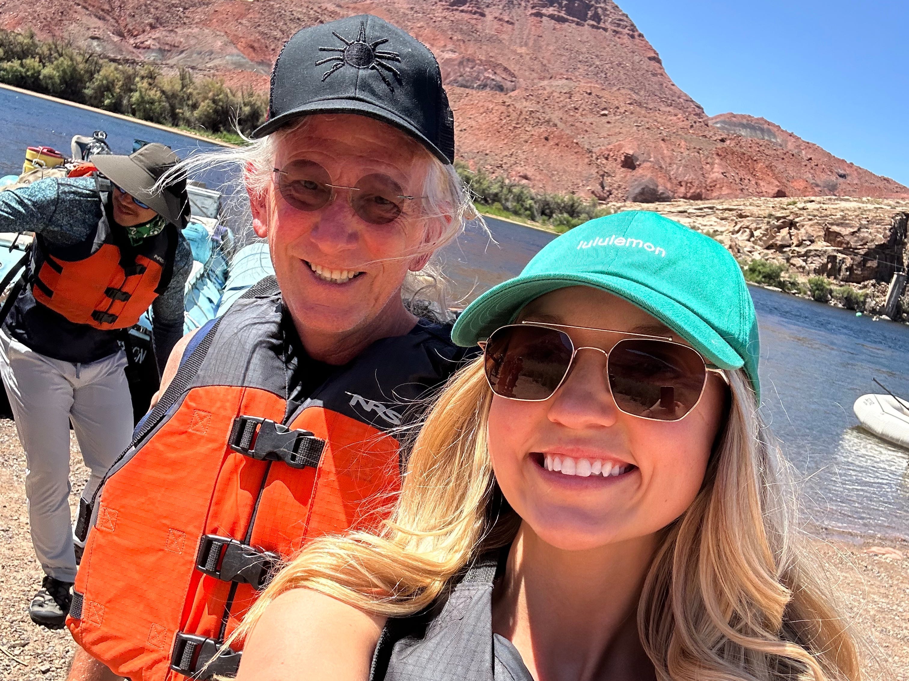 Chloe and her dad smile while wearing life vests.