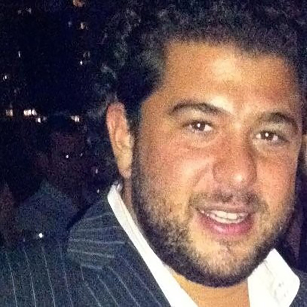 Headshot of paul italia looking at the camera in a dark grey jacket with lighter stripe and white button down