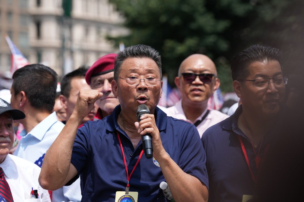 john chan speaking into a microphone at an event