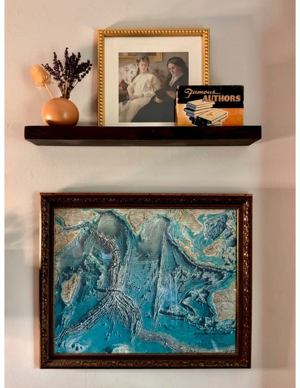 Items that the author scored at garage sales. A shelf with a vase of flowers and a picture and a picture of the ocean.