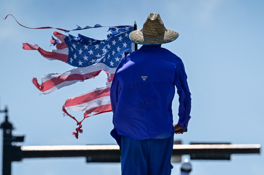 Person holding a tattered American flag during a protest.