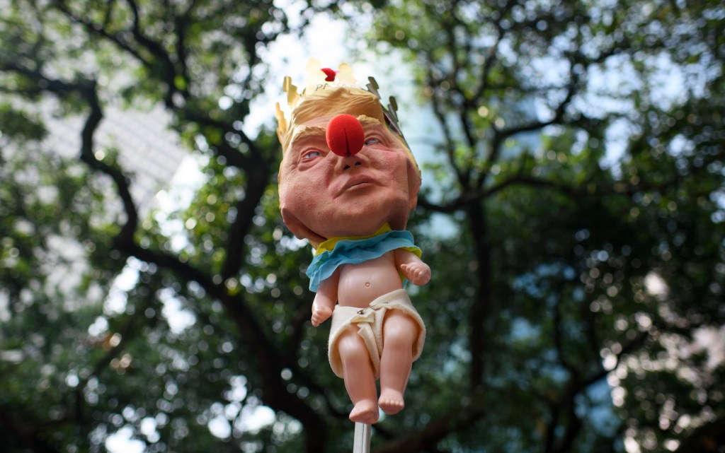 Baby doll with Donald Trump's head wearing a crown and clown nose at a protest.