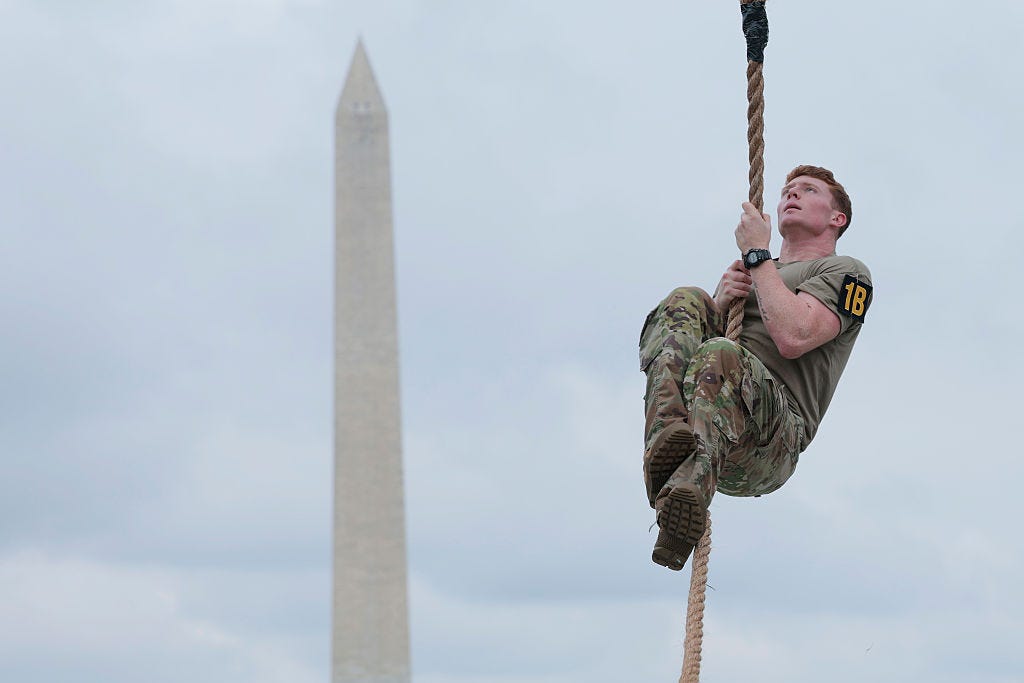 A member of the military climbs a rope during an army fitness competition at the US Army's 250th Anniversary festival.