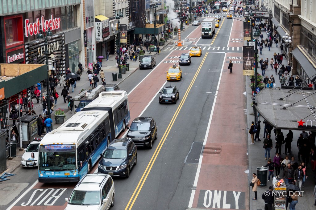 Aerial view of 34th Street in Manhattan, showing bus lanes, traffic, and pedestrians.