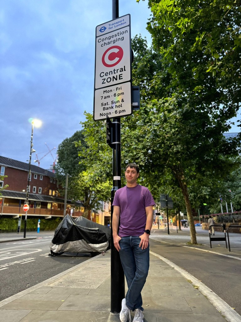 Jason standing by a London congestion charging zone sign.
