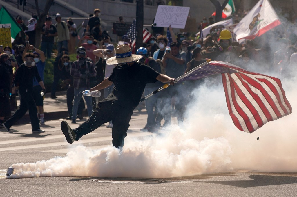 A demonstrator kicks a tear gas canister during a protest in Los Angeles.