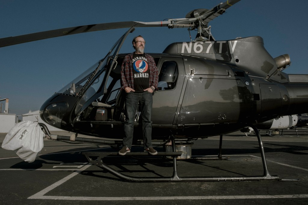 A Los Angeles TV helicopter reporter stands by his helicopter.