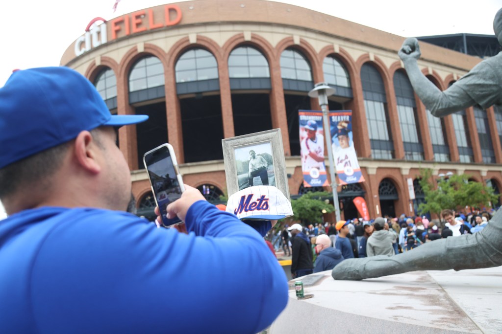 Man taking a photo of his grandfather's picture in front of Citi Field on Father's Day.
