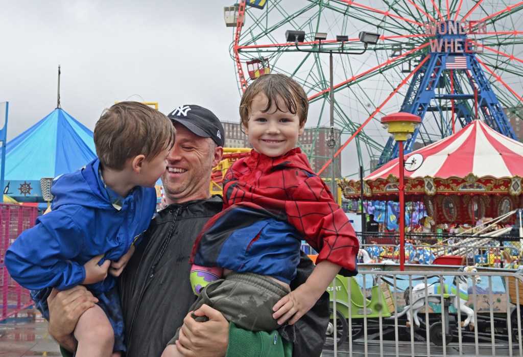 A father and his two sons at Coney Island's Luna Park on a rainy Father's Day.