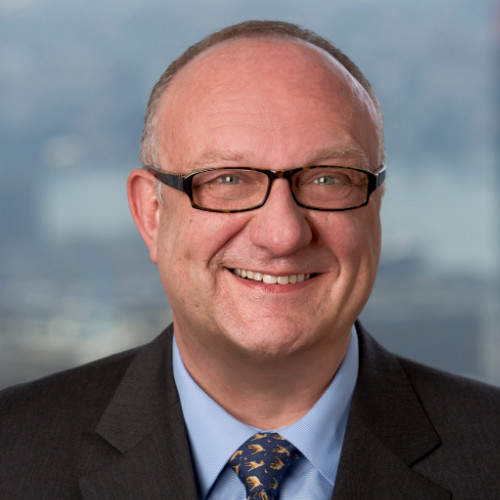 Headshot of a man in a suit and glasses.