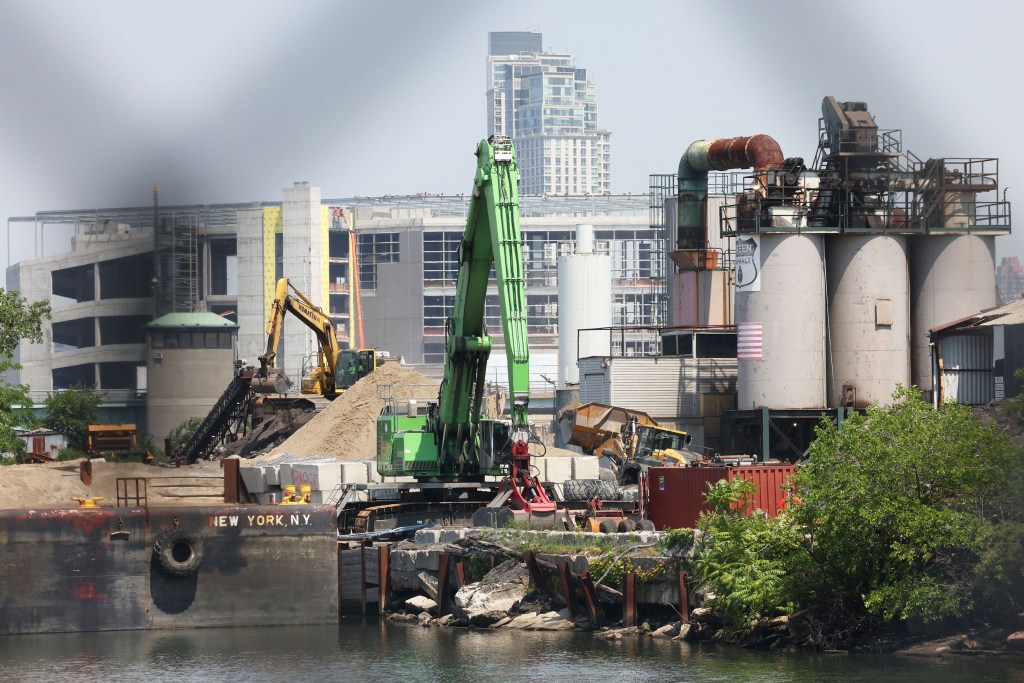 Construction site with large machinery by a body of water.