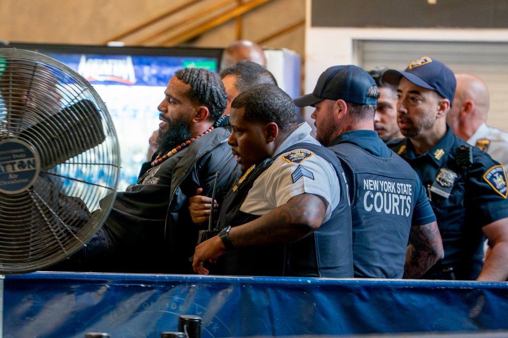 A man in handcuffs being apprehended by court officers.