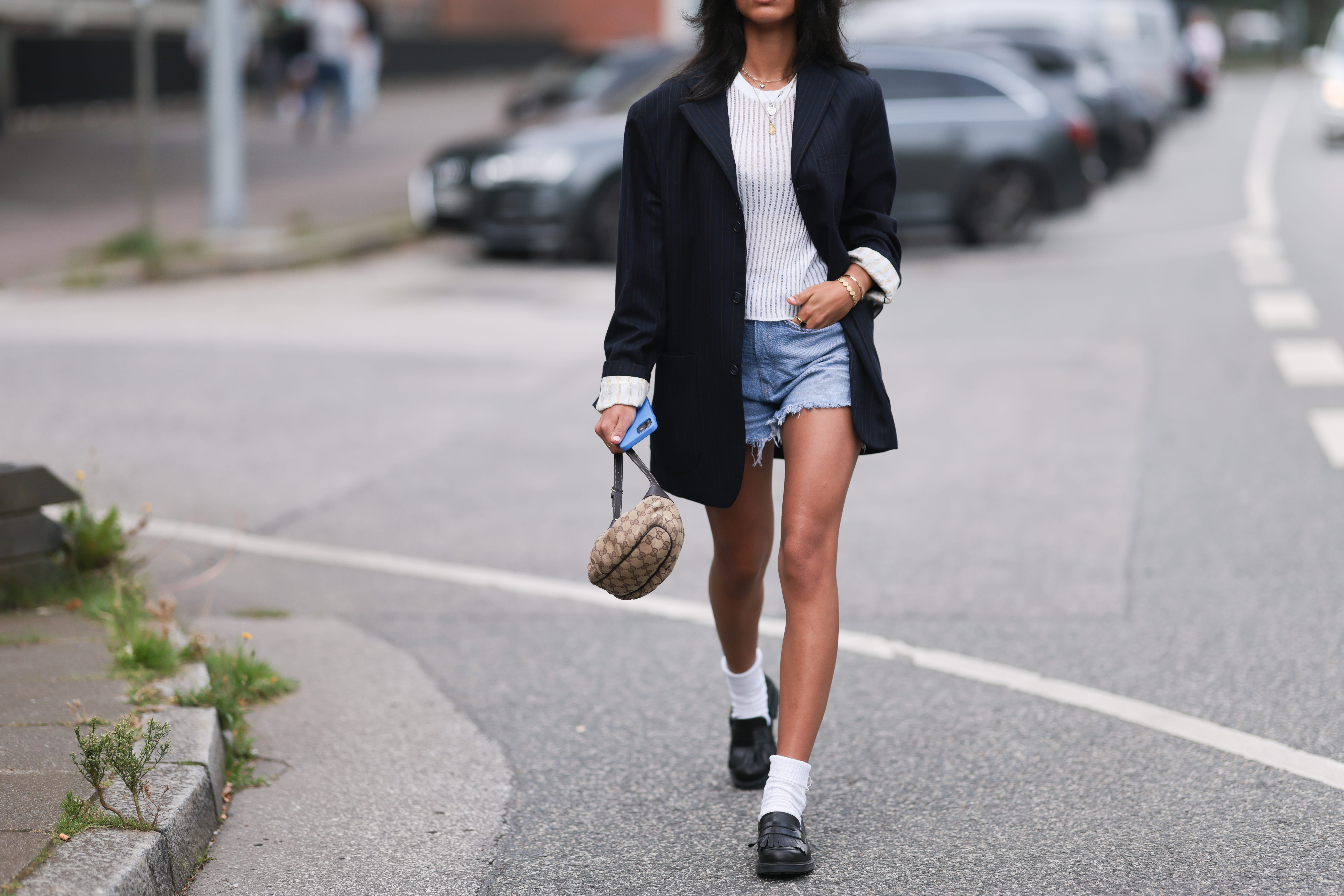 Woman wearing denim cut-off shorts, blazer, loafers with socks