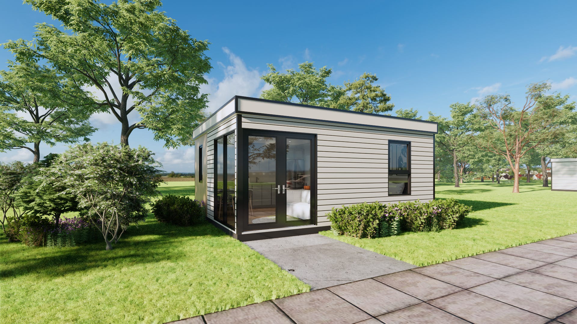 A Hapi tiny home with white panels and windows with black trim sits on a manicured lawn with shrubs and trees around it. The sky is mostly clear and blue. There is a walkway in front of the house.