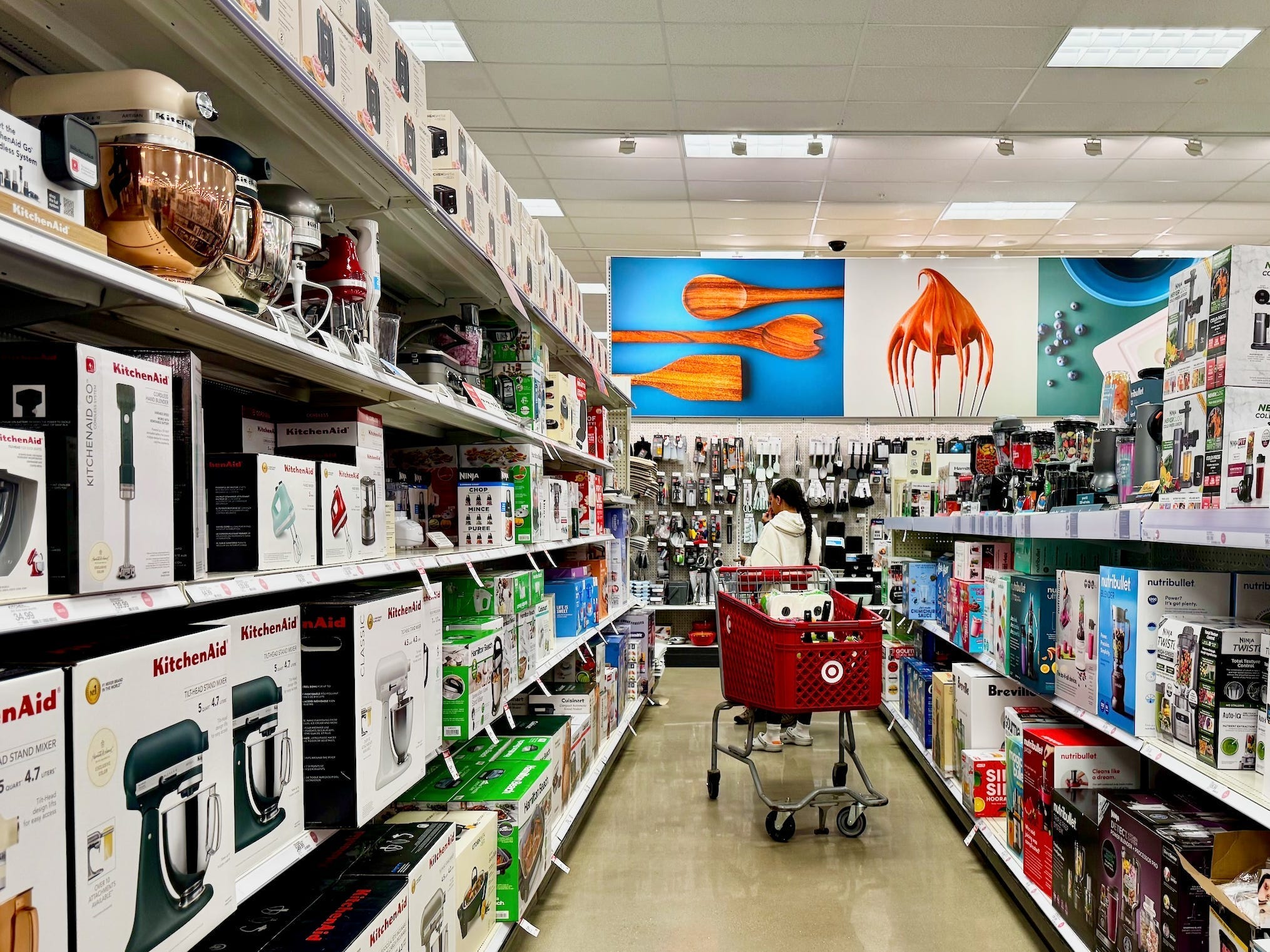 A target store aisle for kitchen appliances, with a woman and a trolly in the aisle.