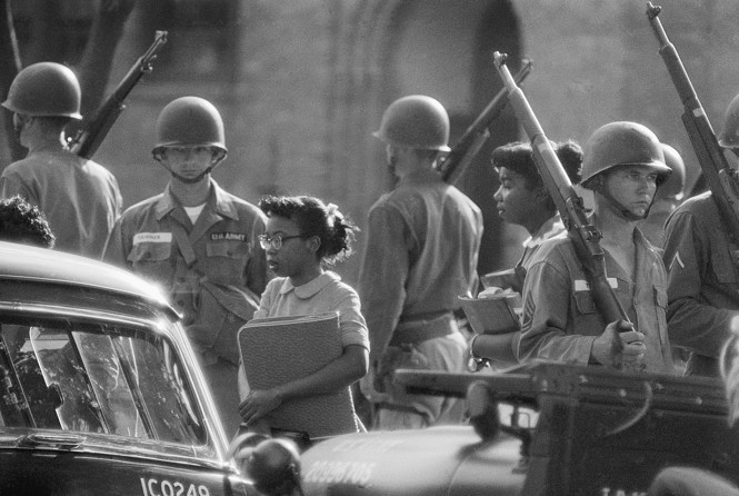 Black students attending Little Rock Central High School escorted By troops in 1957
