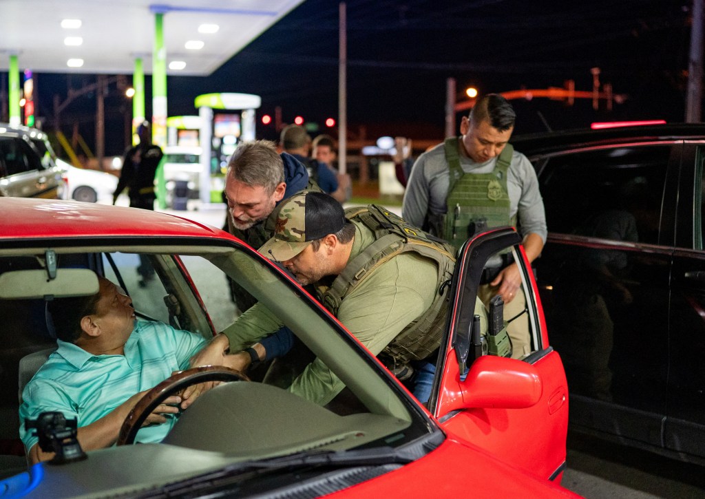ICE officers detaining a man at a gas station.