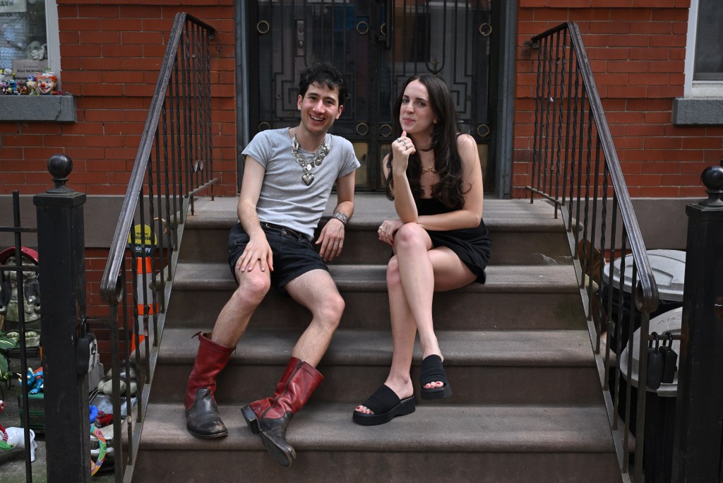 Two people sitting on steps, one wearing red boots and the other wearing black platform sandals.