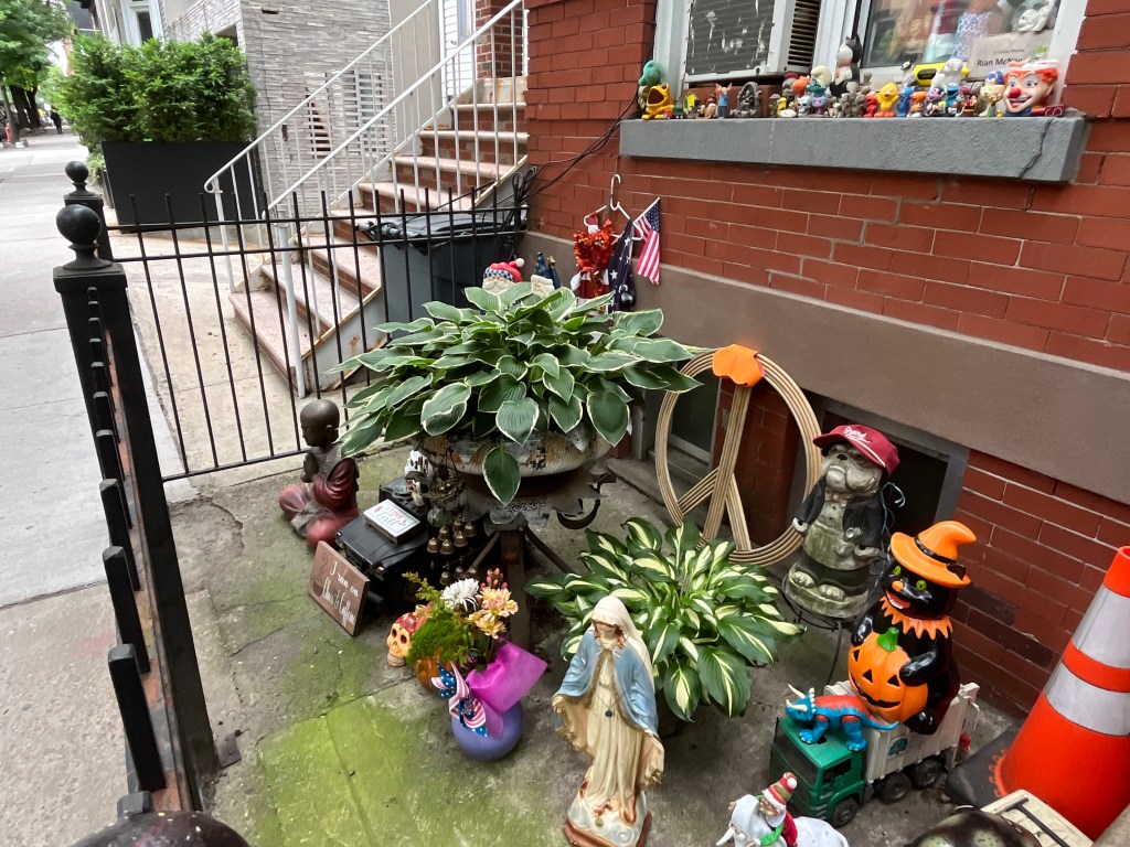 NYC stoop decorated with plants, statues, and figurines.