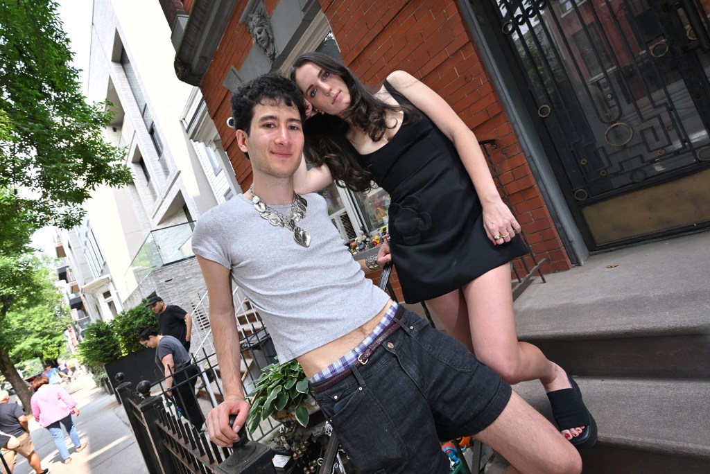 Two people posing on steps outside a brownstone.
