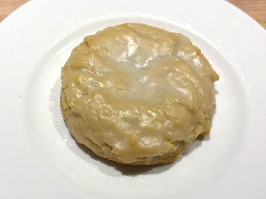 A pale-yellow cookie topped with a glazed icing on a white plate.