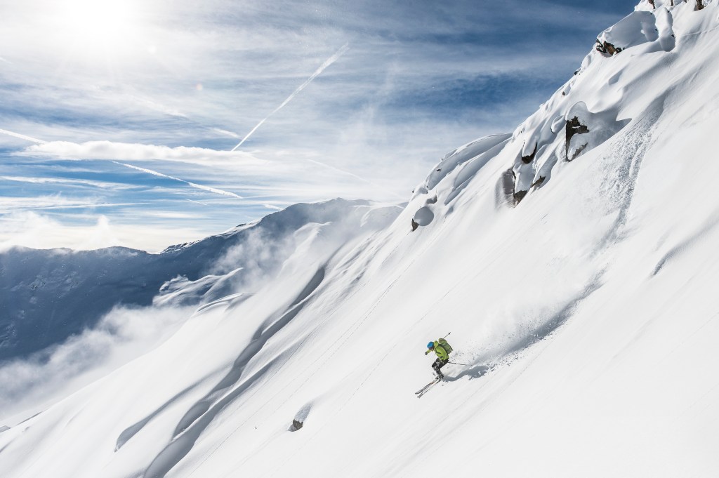 Skier skiing downhill in snowy mountains.