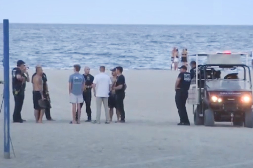 Beachgoers gather near a beach vehicle after a father drowns trying to save his daughter.