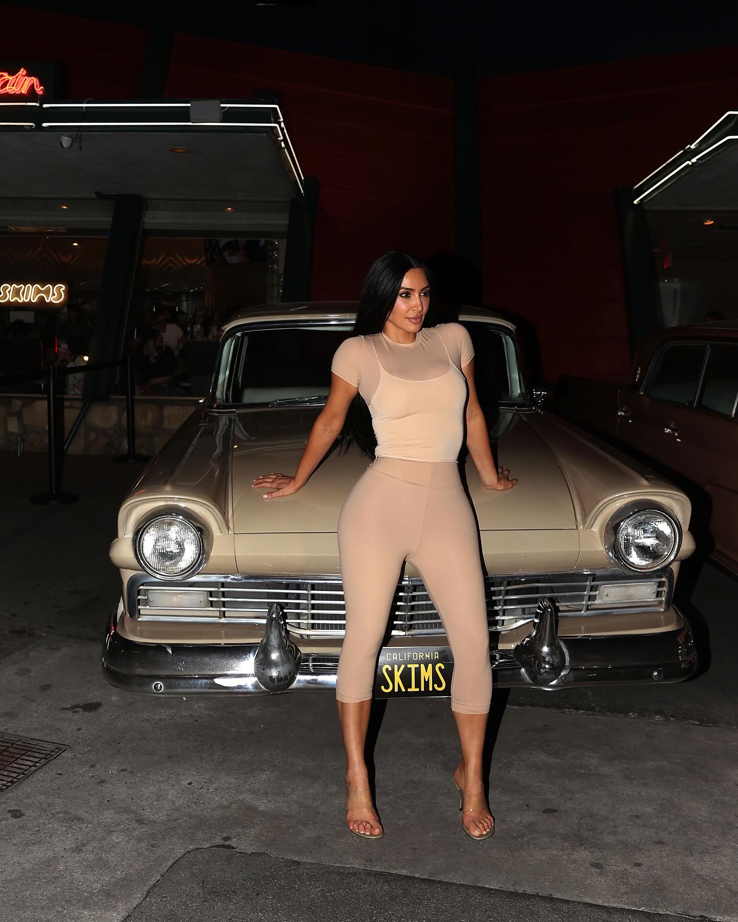 Kim Kardashian poses in front of a car. 