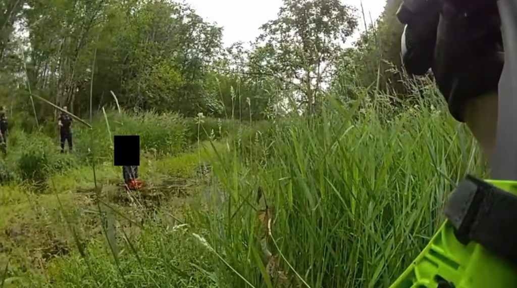 Deputies apprehending a chainsaw-wielding suspect in a wooded area.