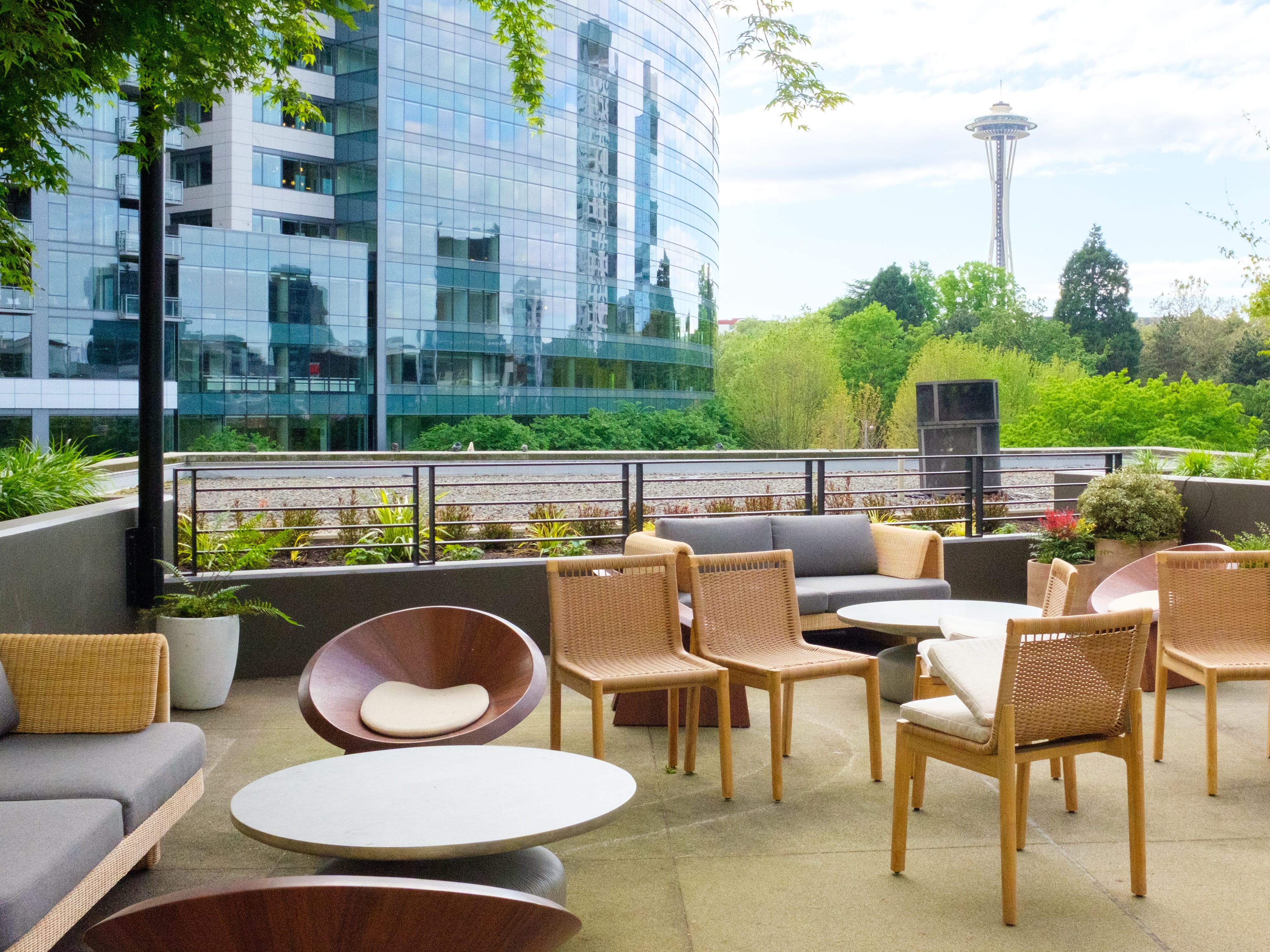 seats and tables on a rooftop terrace with buildings, trees, and the space needed in the background