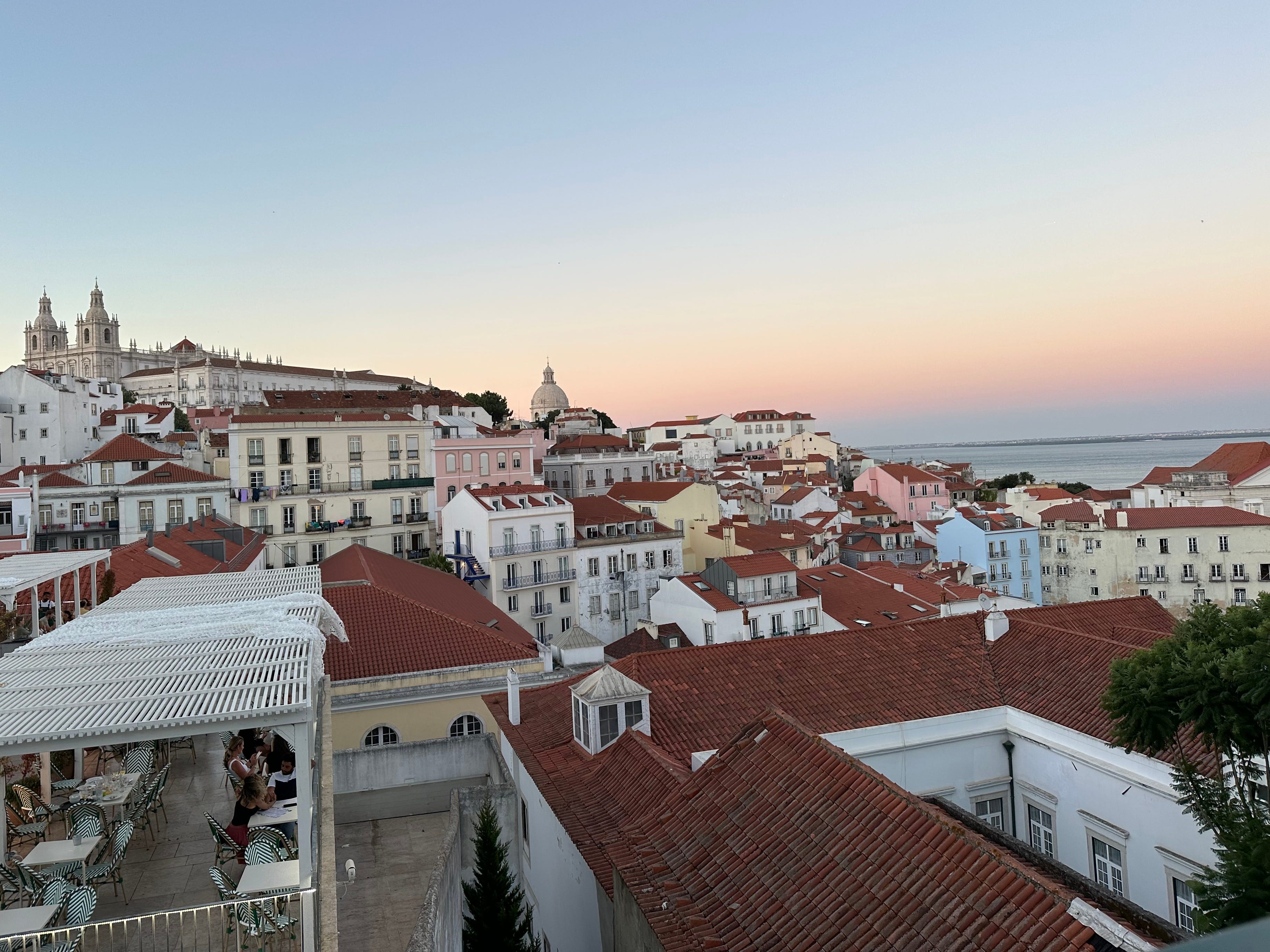 The sunset over red-roofed buildings in Lisbon.