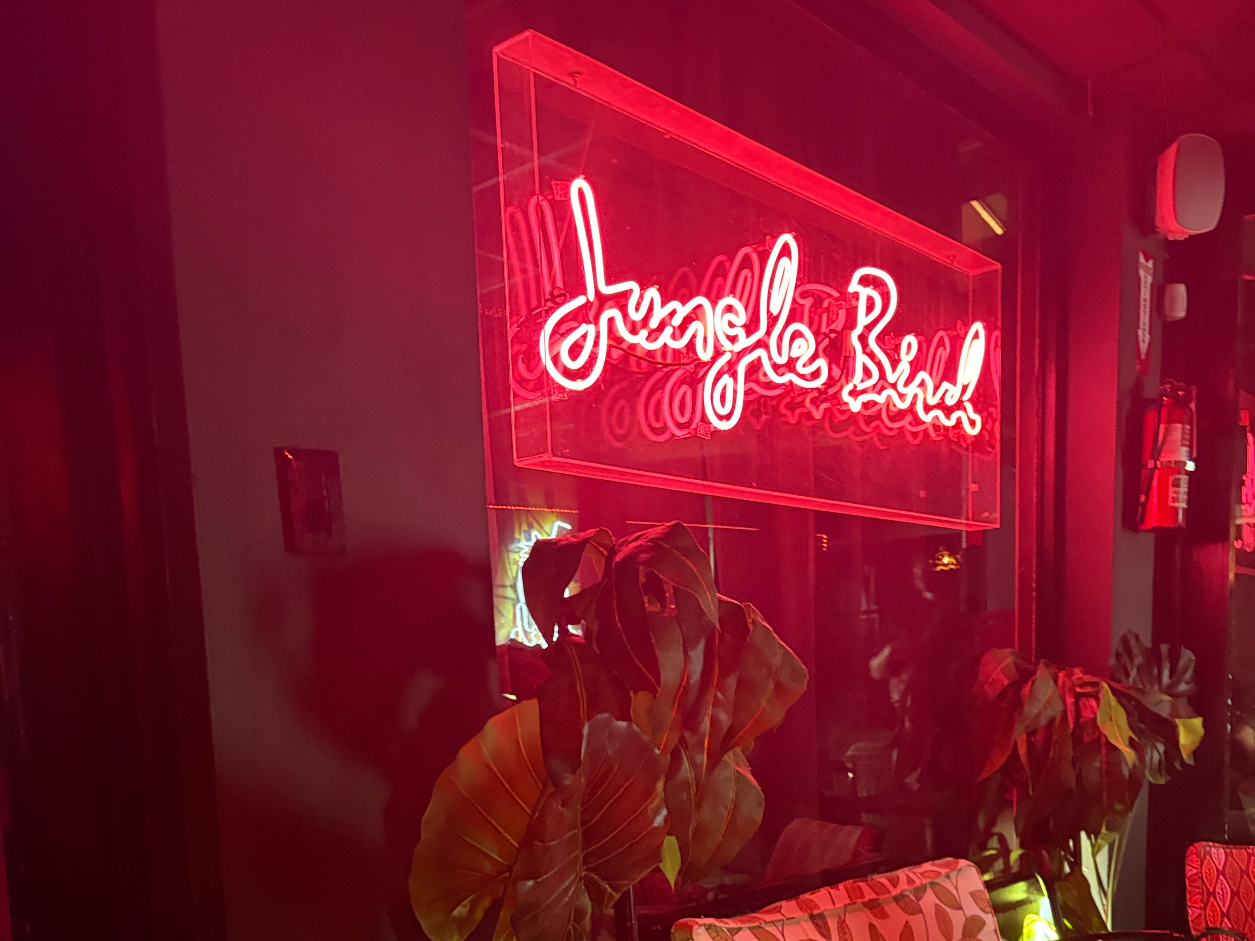 A red neon sign that reads, "Jungle Bird."