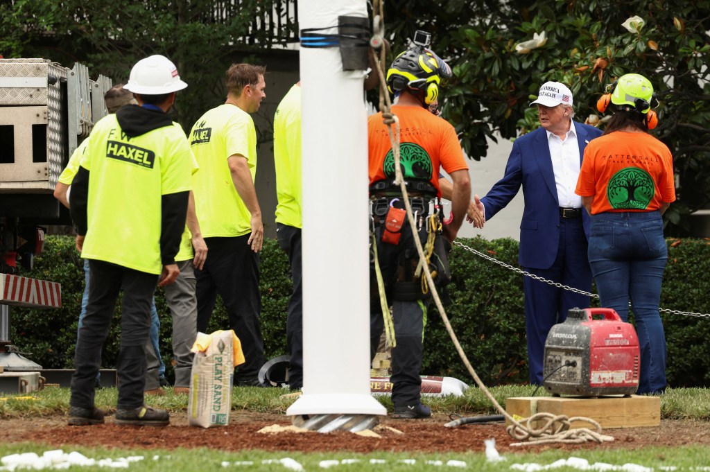 President Trump shaking hands with workers installing a new flagpole on the White House South Lawn.