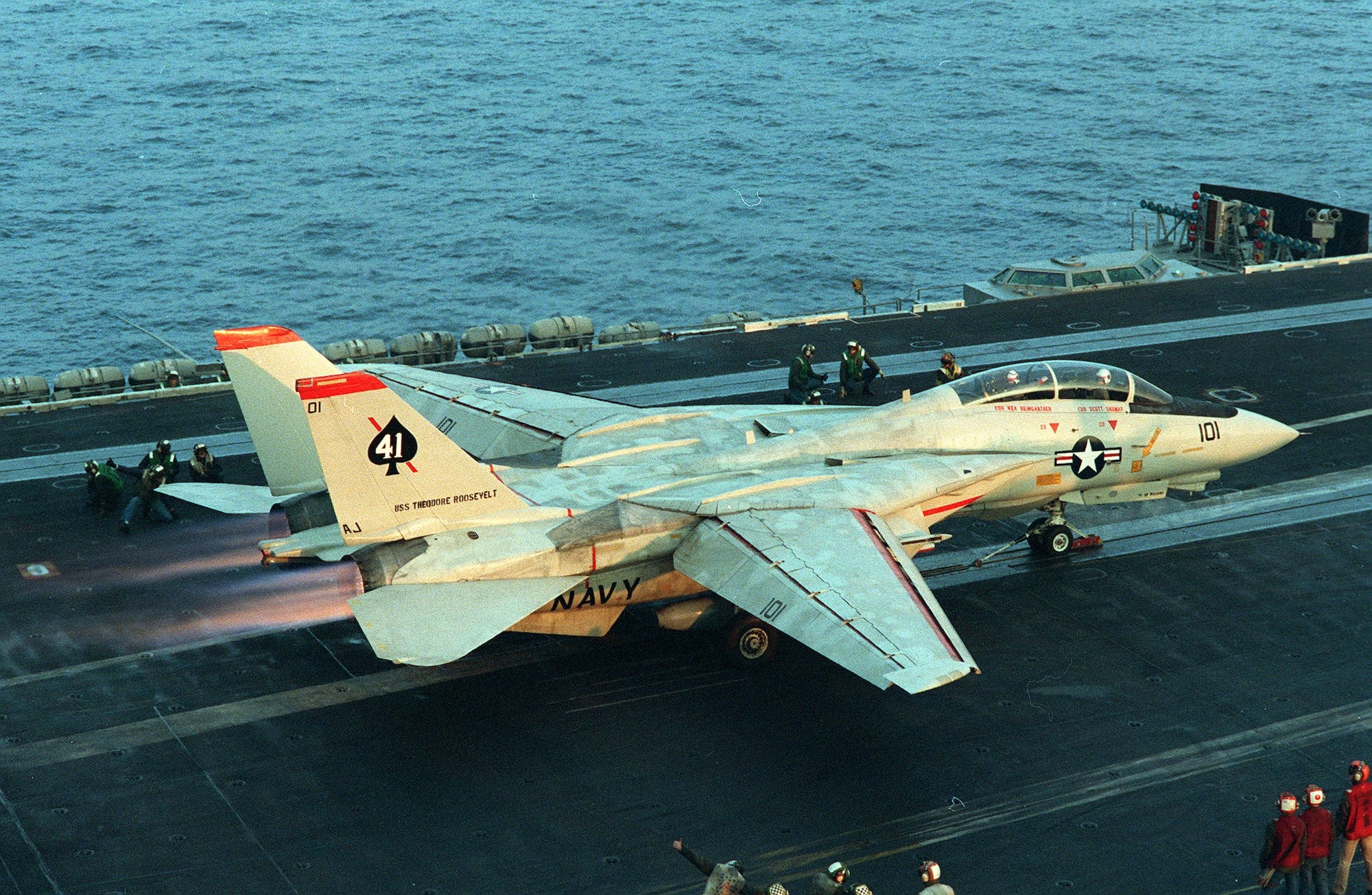 A white fighter jet on top of an aircraft carrier in the sea