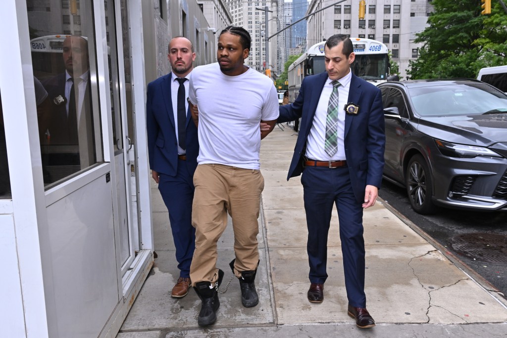 Miguel Jiraud in handcuffs, escorted by police officers.