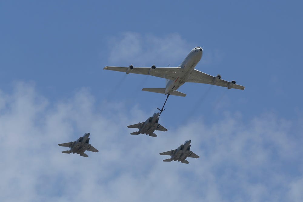 A Boeing 707 refueling tanker in formation with F-15I strike fighters.