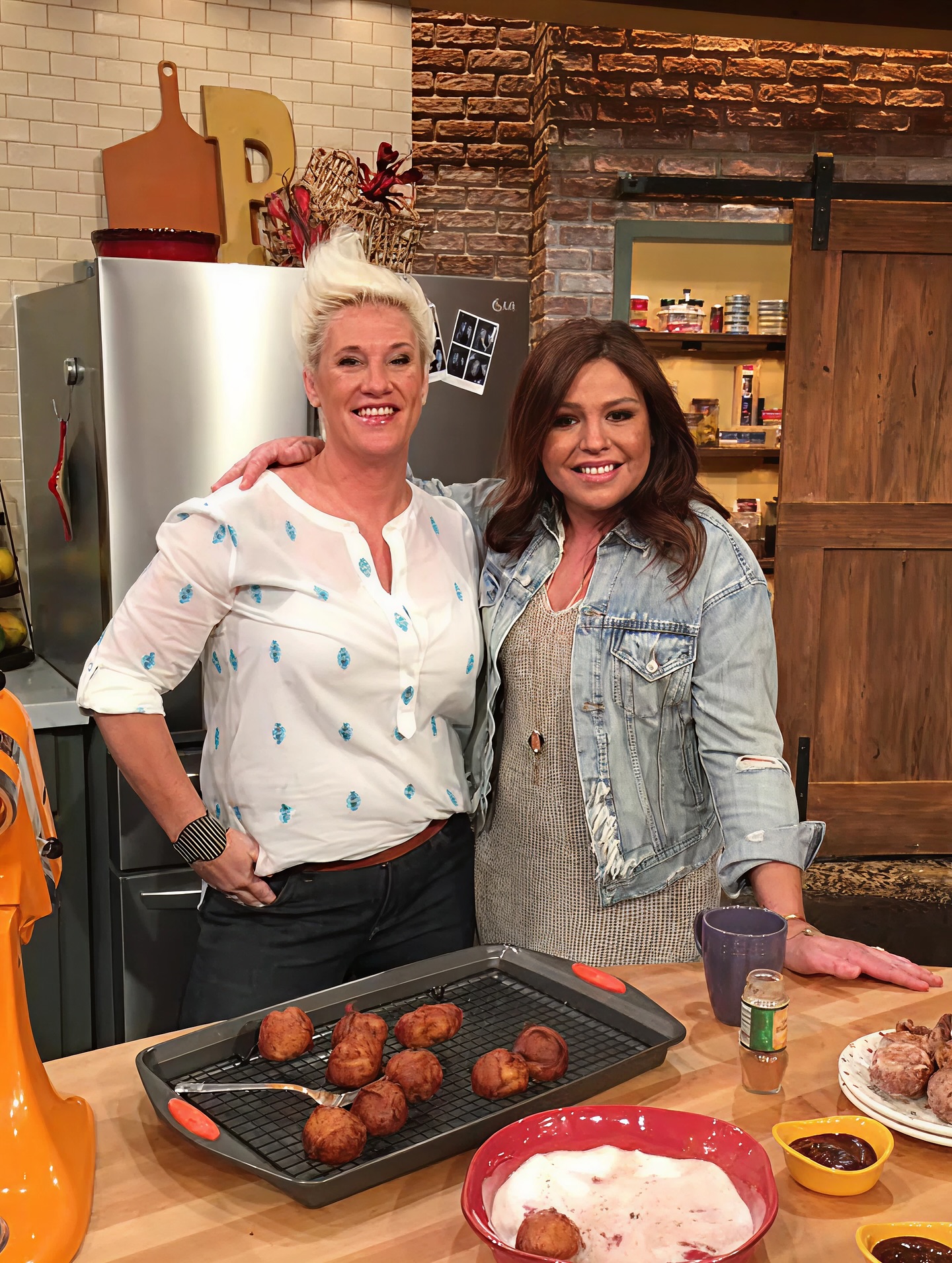 Rachel Ray and Anne Burrell stand together in a kitchen. 