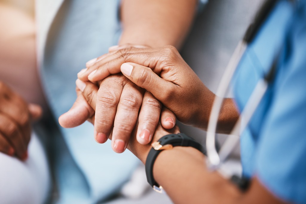 Nurse holding patient's hand.