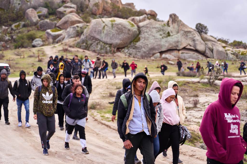 Migrants walking on a dirt road after crossing the U.S.-Mexico border.