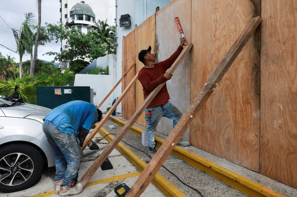 People put up planks of wood against a building as a protection, as hurricane Erick strengthens off Mexico's Pacific Coast, in Acapulco, Guerrero state, Mexico, June 18, 2025.