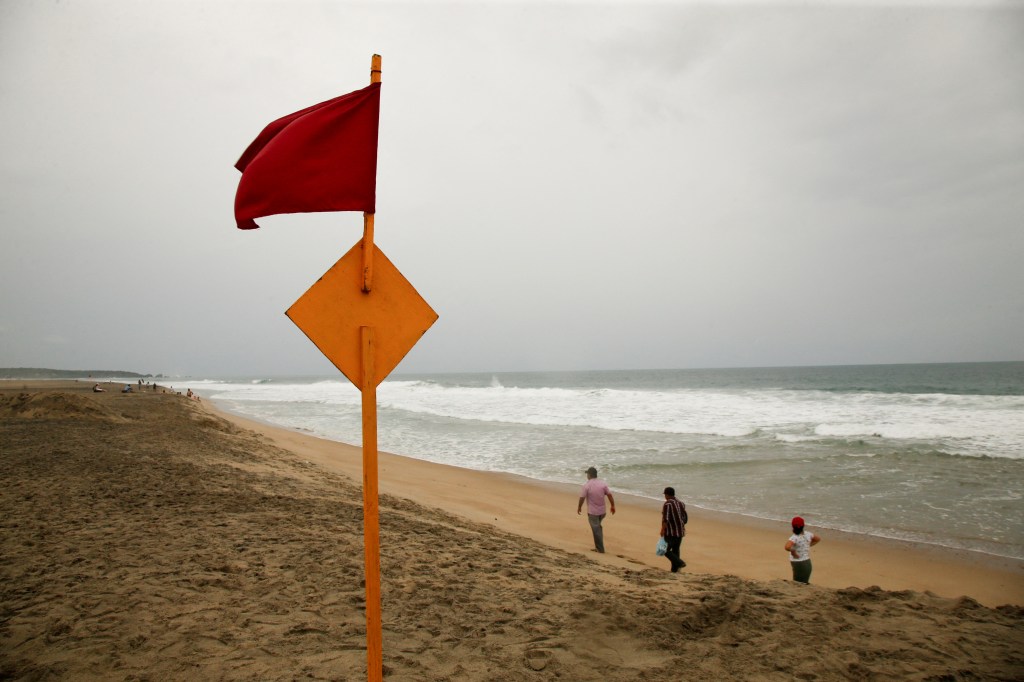 A red flag flutters in the wind, warning beachgoers of dangerous conditions as Hurricane Erick strengthens off Mexico's Pacific Coast, in Puerto Escondido, Oaxaca state, Mexico, June 18, 2025. 