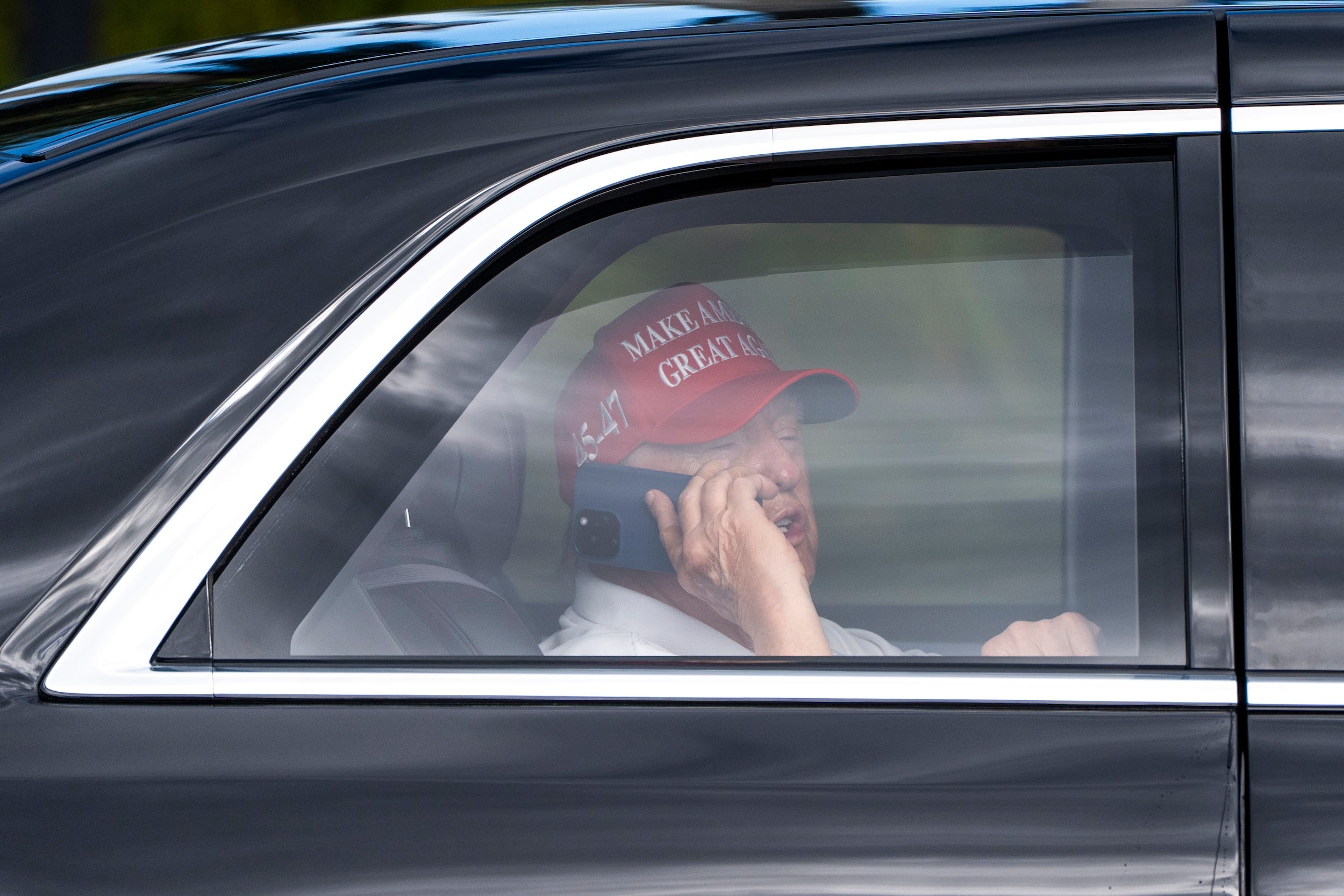 Trump talks on the phone while he arrives at his West Palm Beach golf club