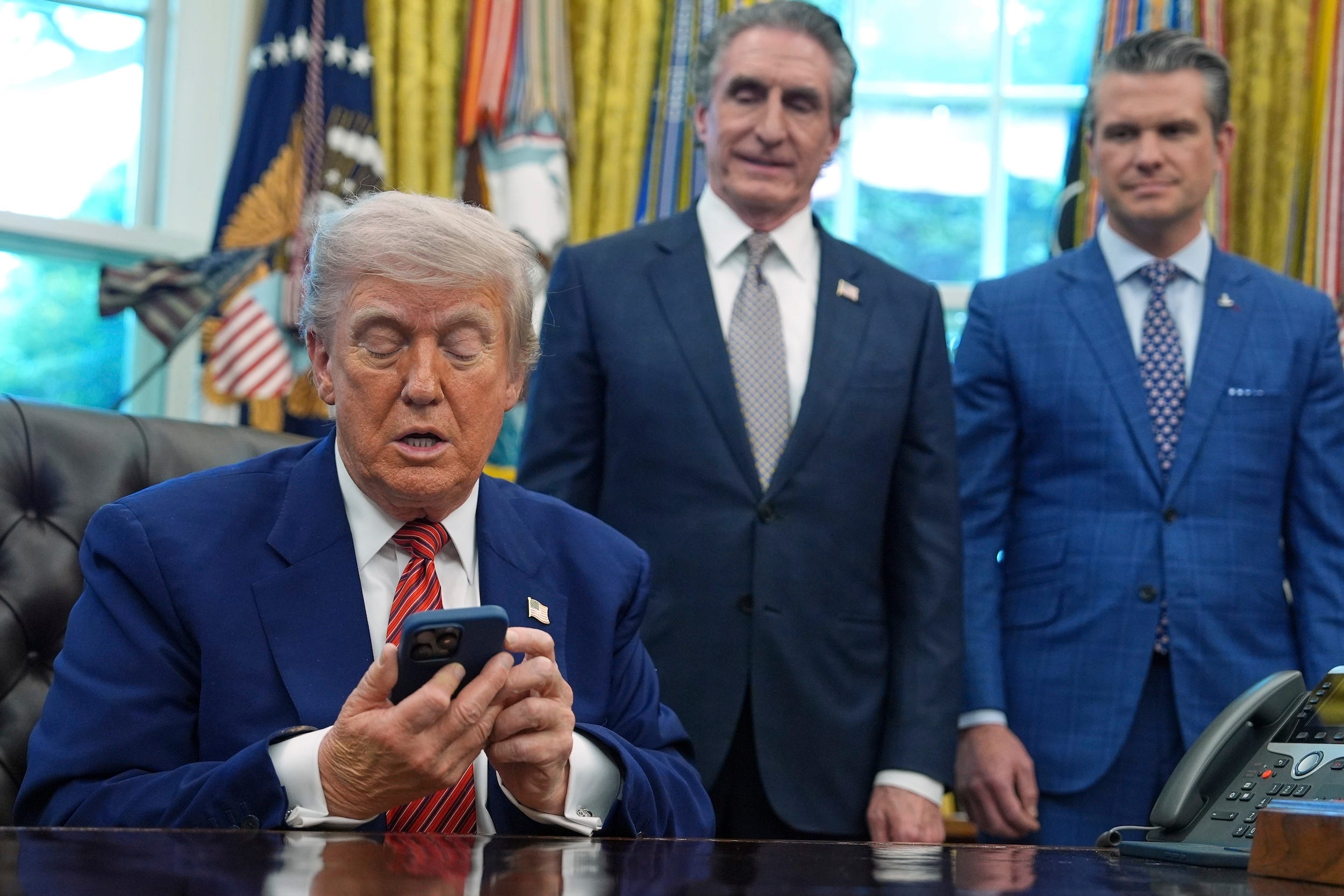 Trump silences his phone during an executive order signing ceremony
