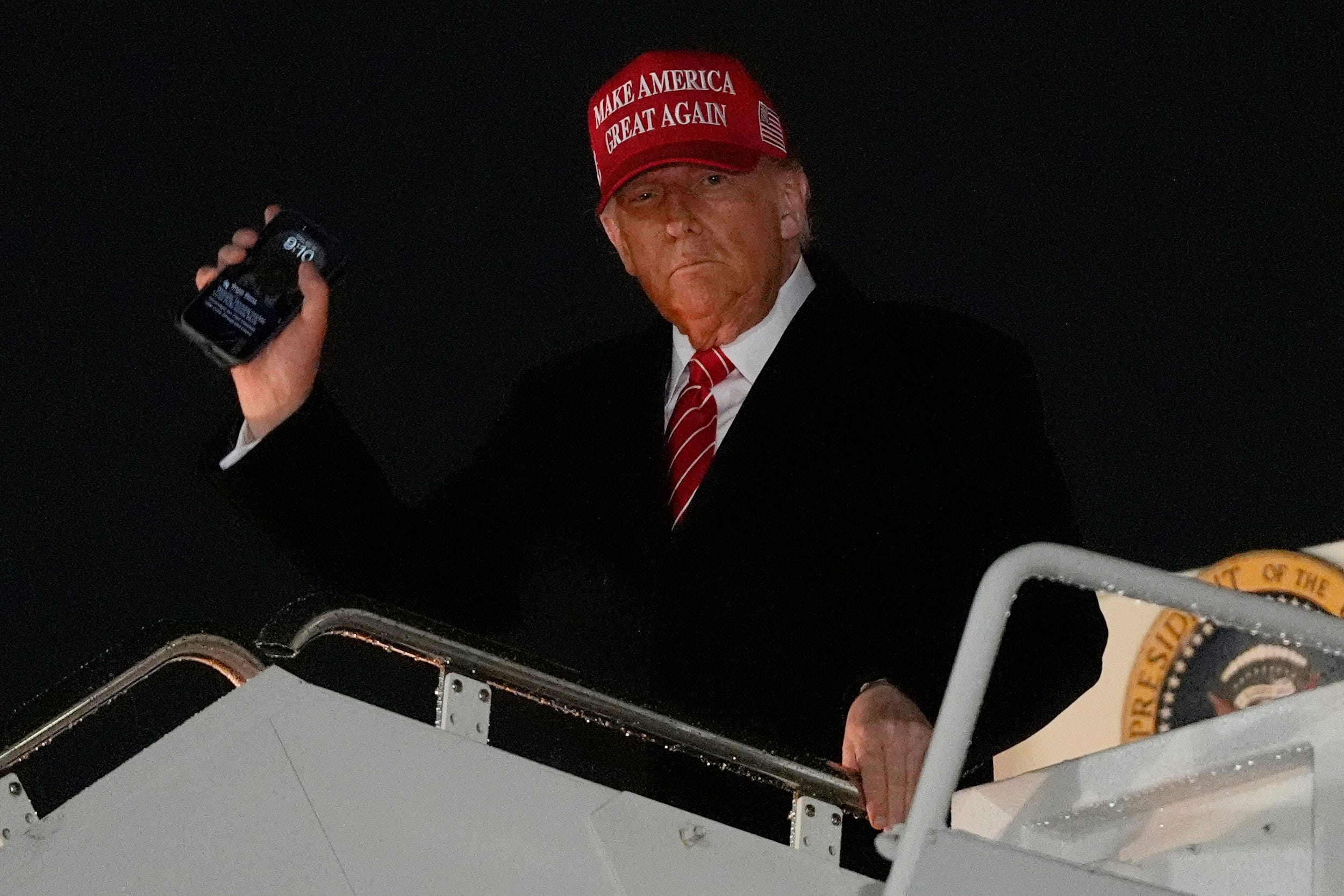 Trump holds his phone as he arrives at Joint Base Andrews