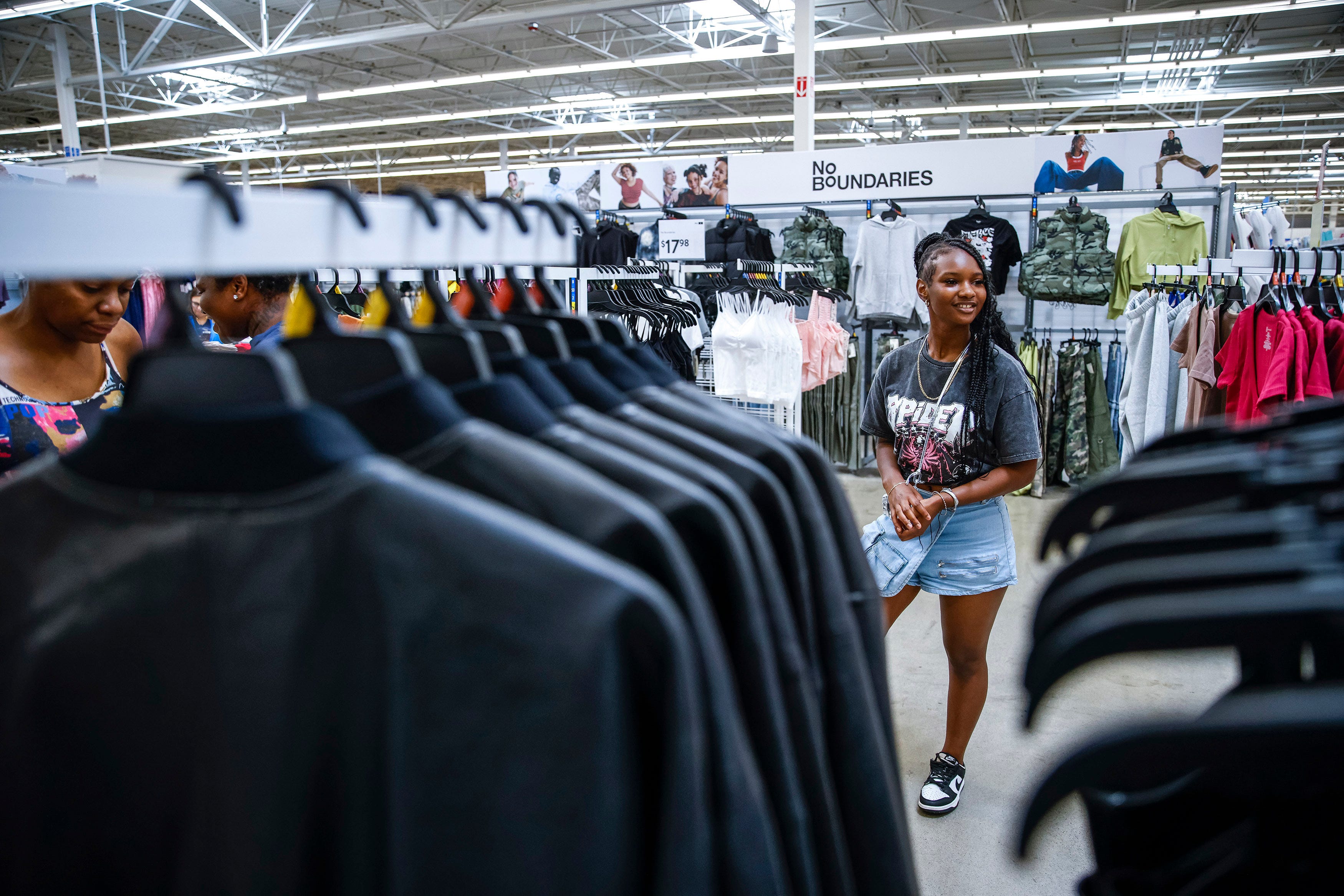 Woman stands in Walmart looking at clothing racks.